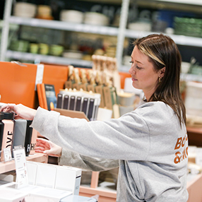 Butiksmedarbejder står og retter til i butikken