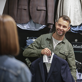 medarbejder fremviser blå blazer med skjorte indenunder til kunde