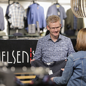 medarbejder ekspederer kunde ved kassen i butik