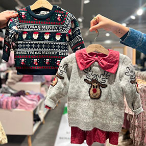 En mørkeblå julesweater med print på af julemanden og en grå julesweater med print på af Rudolf. 