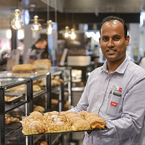 Mand står med et fad med boller